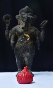 red coconut Ladoo with fresh milk for offering bronze Ganesha statue Hinduism elephant head god worship for luck and success on black background