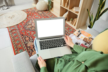 Woman with laptop sitting on sofa at home