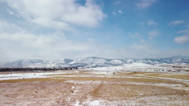 Flying over snowy fields towards the foothills of the Colorado Rockies during the day, aerial