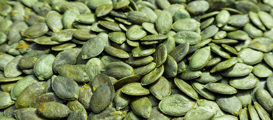 Background texture of green pumpkin seeds. Organic food, selective focus.