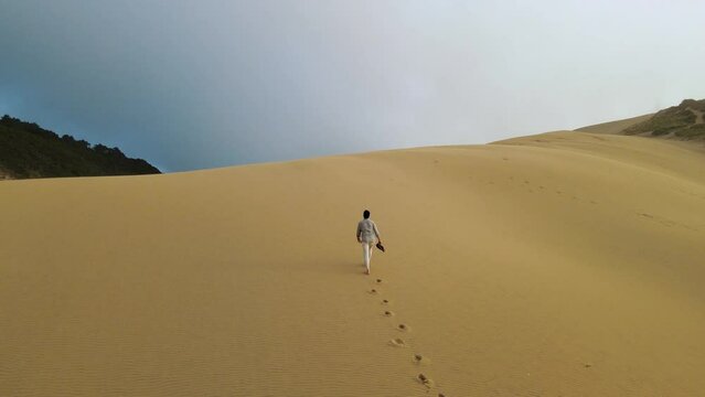 A lonely man walks through the desert and leaves footprints in the sand