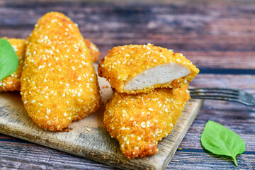 
 Crispy  deep fried   Chicken strips. Breaded  with cornflakes chicken  breast fillets  with chilly peppers and fresh   basil on wooden rustic background
