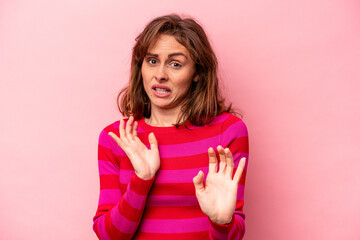 Young caucasian woman isolated on pink background rejecting someone showing a gesture of disgust.