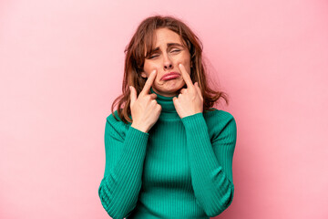 Young caucasian woman isolated on pink background crying, unhappy with something, agony and confusion concept.