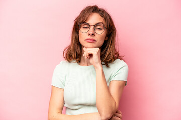 Young caucasian woman isolated on pink background suspicious, uncertain, examining you.