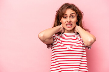 Young caucasian woman isolated on pink background touching back of head, thinking and making a choice.