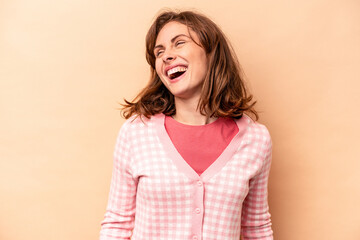 Young caucasian woman isolated on beige background relaxed and happy laughing, neck stretched showing teeth.