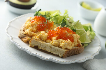 Scrambled eggs with red caviar on toast