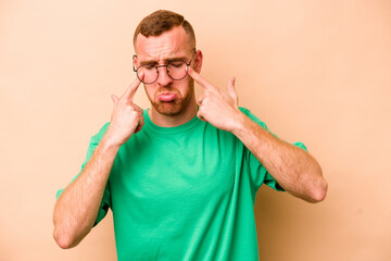Young caucasian man isolated on beige background crying, unhappy with something, agony and...