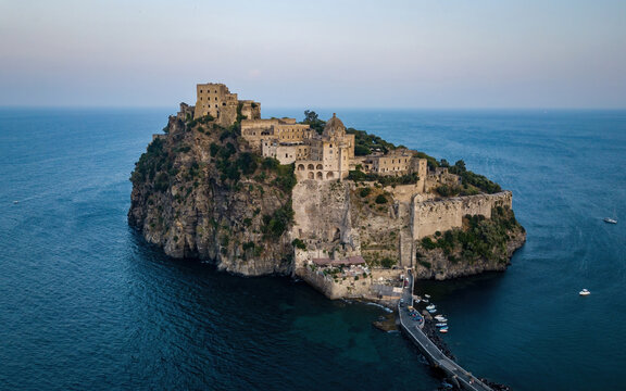 Sant'Angelo seaside castle on an island at blue sea on a sunset (aerial drone photo). Mediterranean, Ischia island, Italy