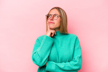 Young caucasian woman isolated on pink background contemplating, planning a strategy, thinking about the way of a business.