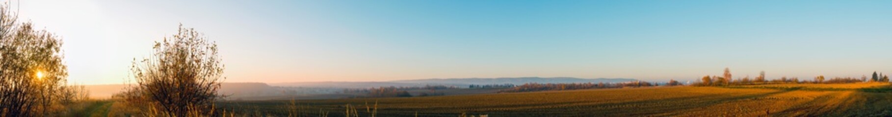 Panorama of plowed field on a background of the sun