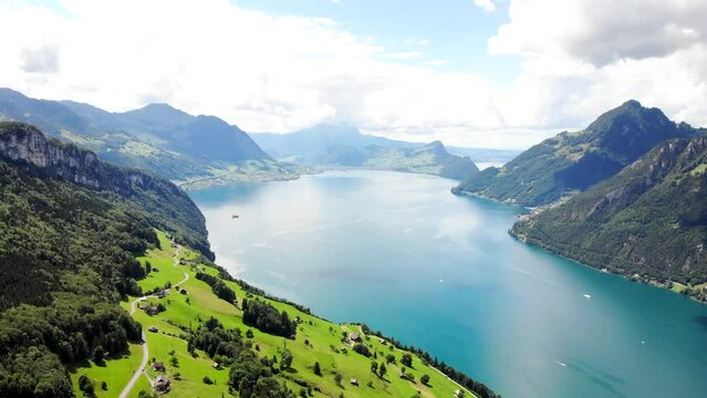Aerial flyover over the vibrant green shores of Lake Lucerne on a sunny summer day near Seelisberg in Uri, Switzerland