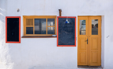 Greek island, Cycladic shop with menu blank board. Chalkboard on whitewashed wall outdoors.