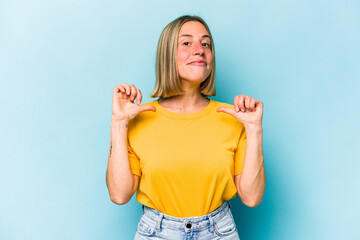 Young caucasian woman isolated on blue background feels proud and self confident, example to follow.