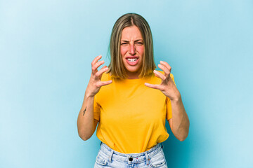 Young caucasian woman isolated on blue background upset screaming with tense hands.