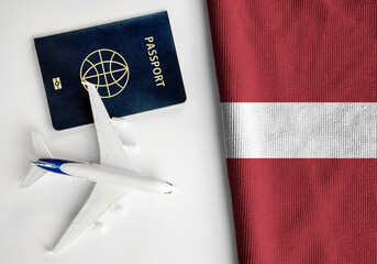 Flag of Latvia with passport and toy airplane. Flight travel concept  - obrazy, fototapety, plakaty