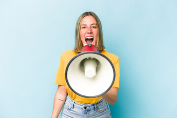 Young caucasian woman holding a megaphone isolated on blue background