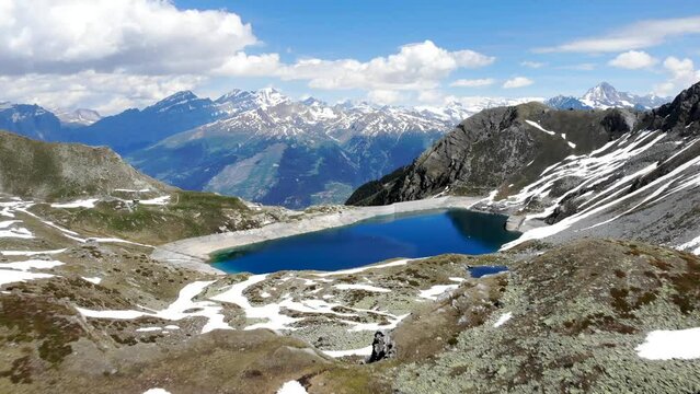 Aerial flyover over lake Illsee near St. Luc in Valais, Switzerland at the beginning of summer with melting snow around