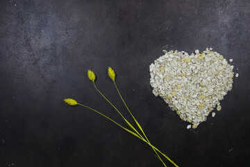 Oatmeal heart isolated on a dark background, with place for an inscription. Bunting heart symbol. Heart of cereals. Healthy eating. heap of oat flakes in a shape of heart shot from above