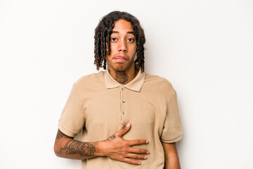 Young African American man isolated on white background touches tummy, smiles gently, eating and satisfaction concept.