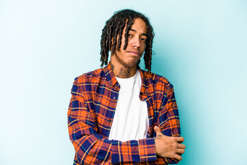 Young African American man isolated on blue background suspicious, uncertain, examining you.