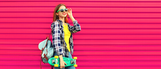 Portrait of stylish teenager girl with skateboard looking away wearing shirt, backpack on vivid pink background, blank copy space for advertising text