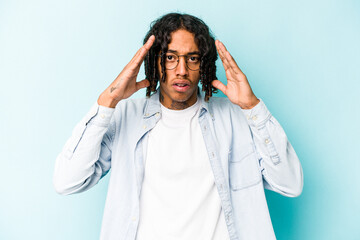 Young African American man isolated on blue background celebrating a victory or success, he is surprised and shocked.