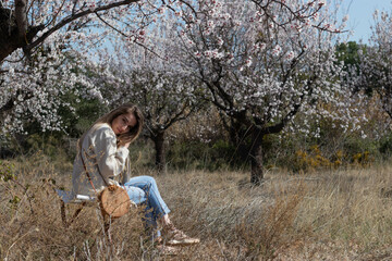 Young and beautiful woman looking at camera sitting in a field with flowers