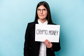 Young caucasian business woman holding a crypto money placard isolated on blue background confused, feels doubtful and unsure.