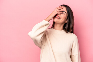 Young caucasian woman isolated on pink background laughing happy, carefree, natural emotion.