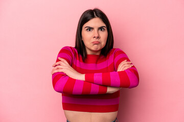 Young caucasian woman isolated on pink background shrugs shoulders and open eyes confused.