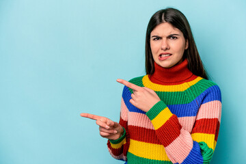 Young caucasian woman isolated on blue background shocked pointing with index fingers to a copy...
