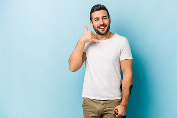 Young man with crutches isolated on blue background showing a mobile phone call gesture with fingers.