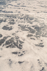 Sea water from a wave with foam on the seashore