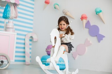 
little girl with two ponytails rides a toy horse