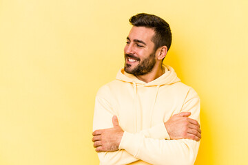 Young caucasian man isolated on yellow background smiling confident with crossed arms.
