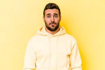Young caucasian man isolated on yellow background sad, serious face, feeling miserable and displeased.
