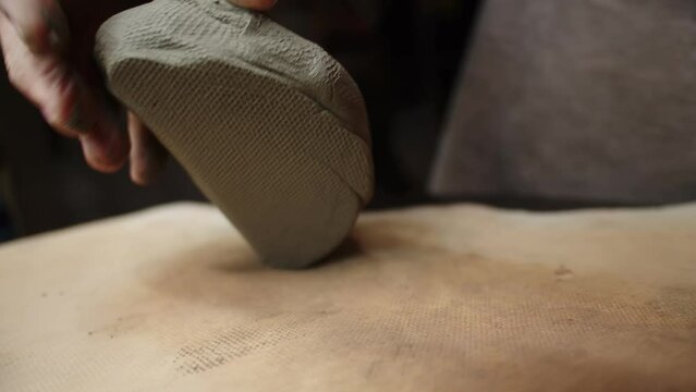Male hands of artisan potter crumple and roll clay on table, preparing it for processing on desktop. Needleworker kneads clay with his hand. Concept art