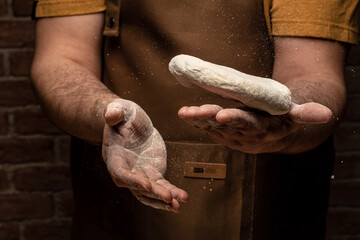 man kneading dough, baker with flour. Beautiful and strong men's hands knead the dough make bread, pasta or pizza. Powdery flour flying into air