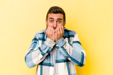 Young caucasian man isolated on yellow background biting fingernails, nervous and very anxious.