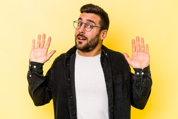 Young caucasian man isolated on yellow background being shocked due to an imminent danger
