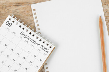 September 2022 desk calendar with blank paper sheet for your text or message on wooden background.