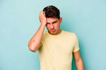 Young caucasian man isolated on blue background tired and very sleepy keeping hand on head.