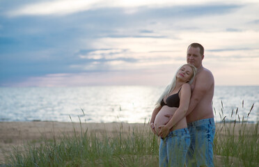 Latvian couple happily standing at the beach during sunset - obrazy, fototapety, plakaty