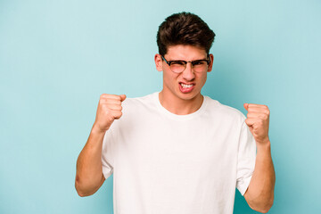 Young caucasian man isolated on blue background upset screaming with tense hands.