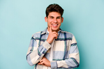 Young caucasian man isolated on blue background smiling happy and confident, touching chin with hand.