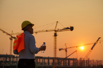 Silhouettes of engineers and workers working at a real estate project site in an industrial building. Preparing to finish work in the evening