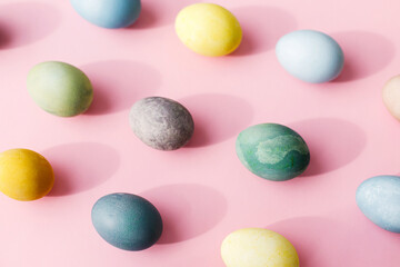 Easter composition. Stylish eggs flat lay on pink background. Modern natural dyed colorful easter eggs layout in sunny light and shadow. Greeting card, easter background