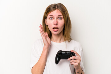 Young English woman playing with a video game controller isolated white background surprised and shocked.